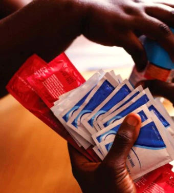 Hands holding multiple packets of condoms in red and blue